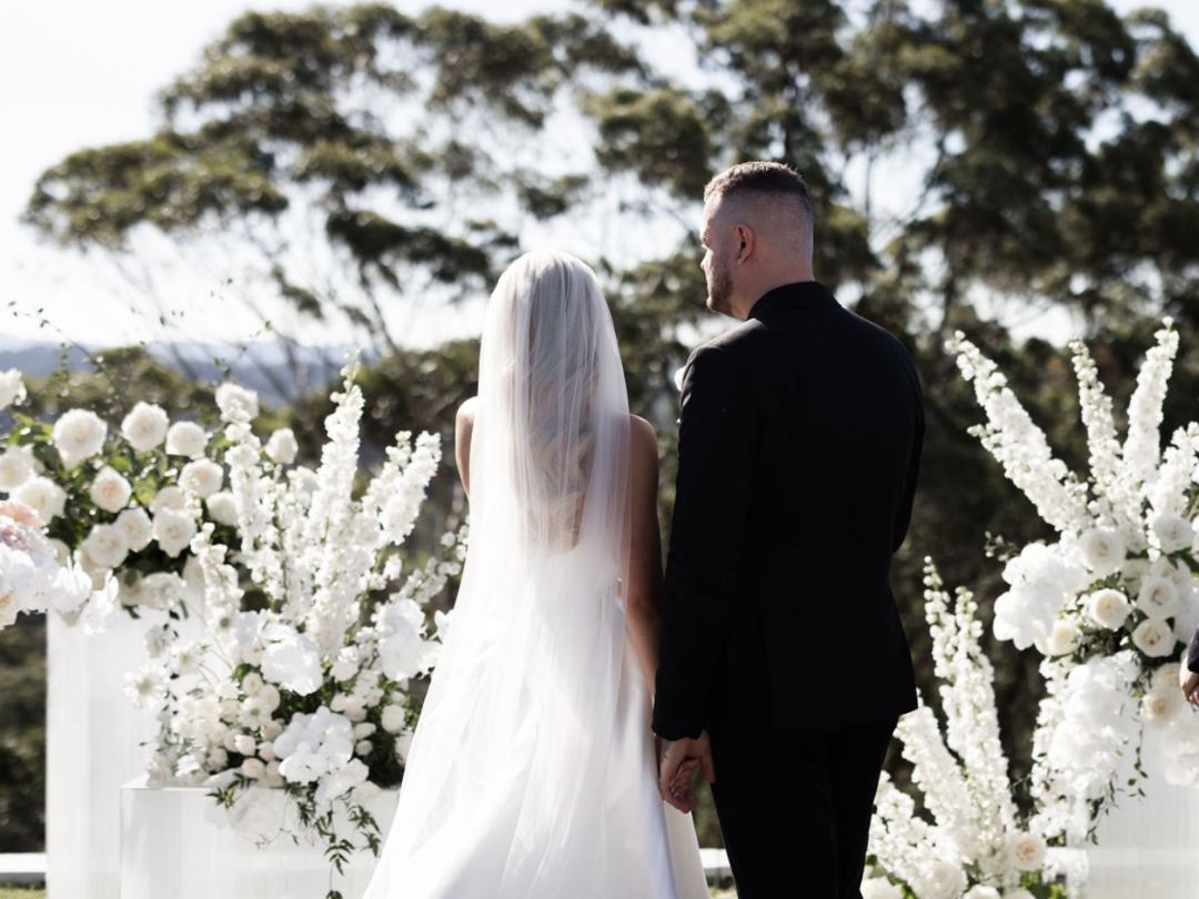Bride and groom with backs to the camera and white flowers in the background
